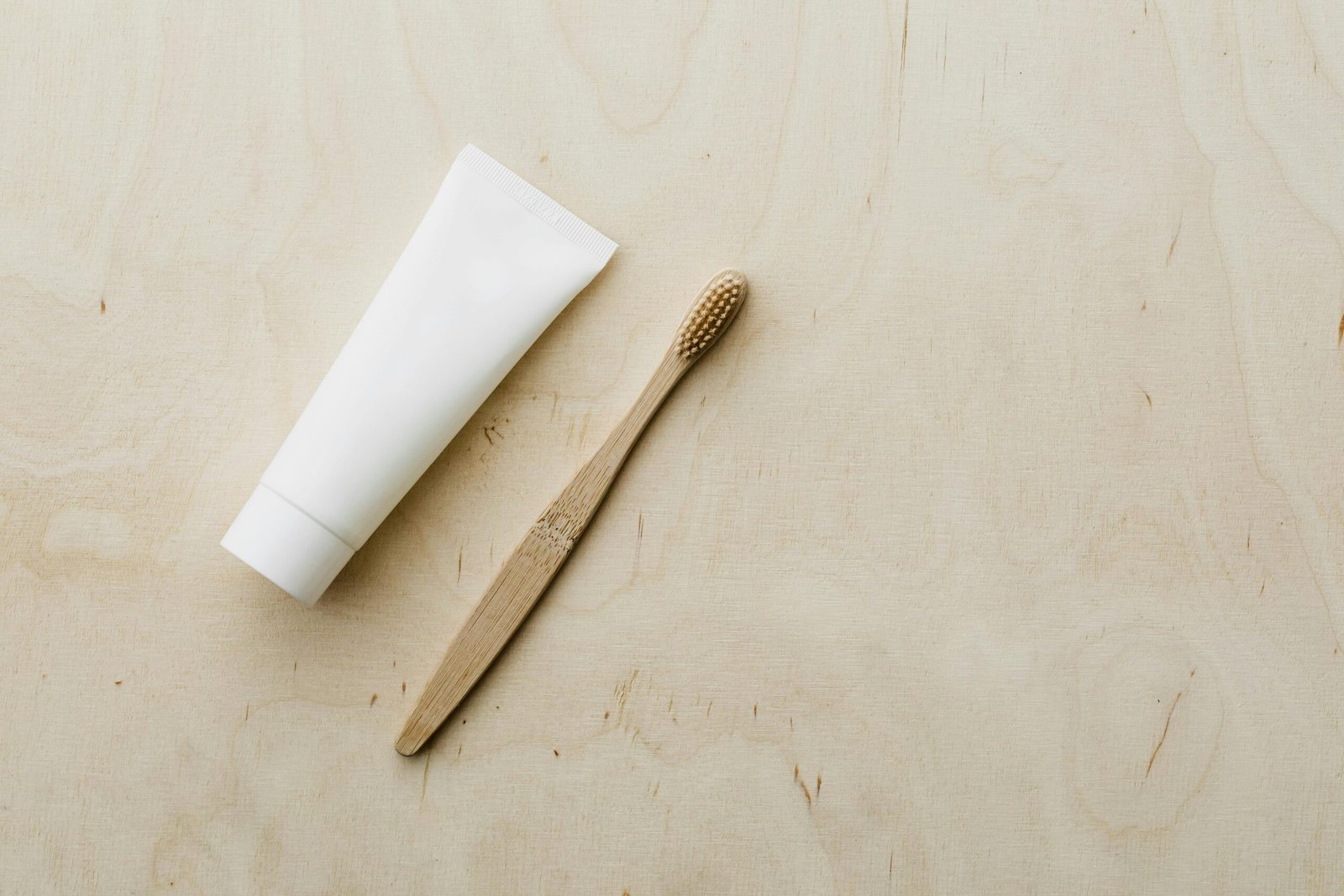 Eco-friendly bamboo toothbrush and toothpaste on a wooden surface.